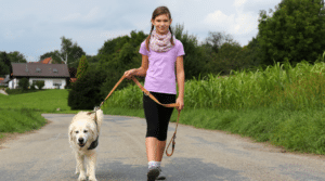 Halterin führt ihren angeleinten Hund beim Spaziergang